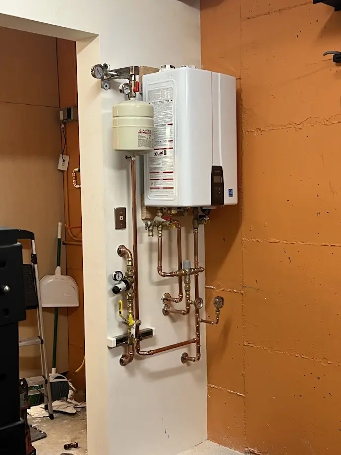 Plumbing technician inspecting water heater connections in Delphi